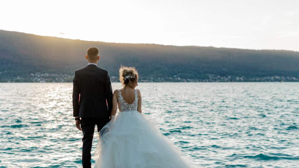 photo-mariage-romantique-annecy Couple de mariés face au lac d’Annecy au coucher du soleil en Haute-Savoie