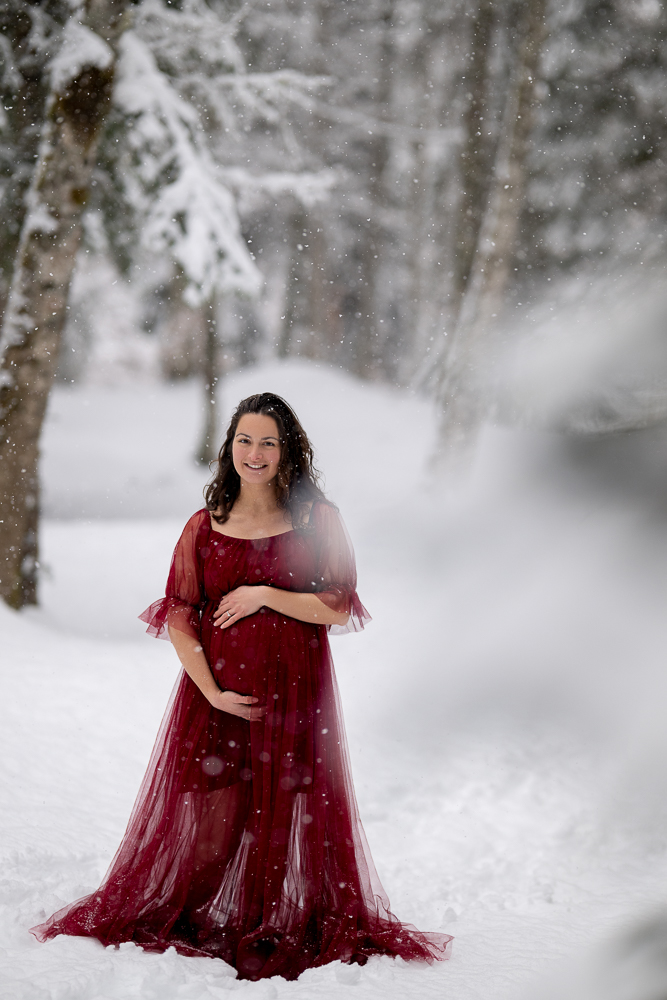 Portrait femme enceinte souriante sous la neige séance grossesse extérieure montagne Haute-Savoie lumière douce hiver