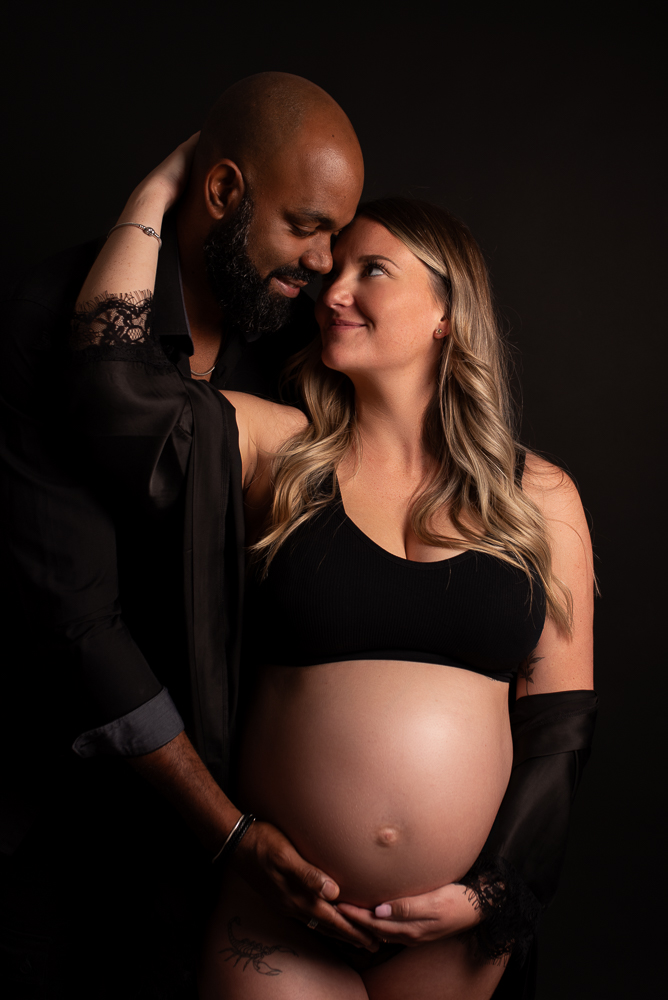 Couple attendant un bébé en séance grossesse en studio en Haute-Savoie avec lumière douce et ambiance intime