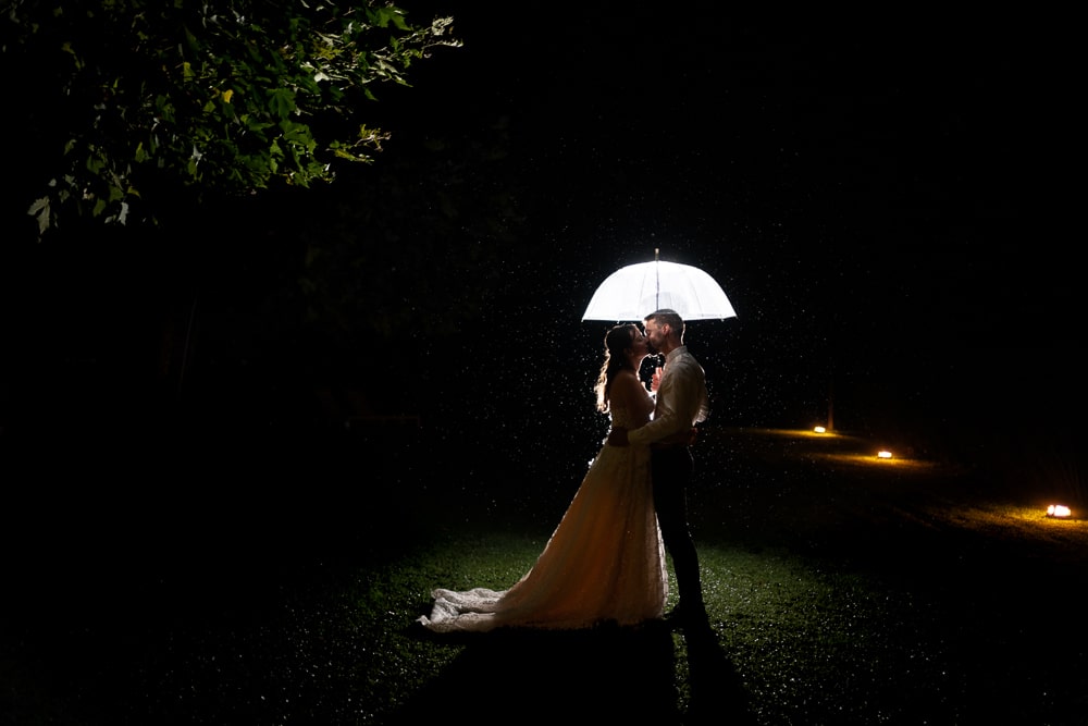 photo-mariage-soiree-lac-annecy Couple de mariés sous un parapluie lumineux lors d’une séance photo de nuit au lac d’Annecy en Haute-Savoie