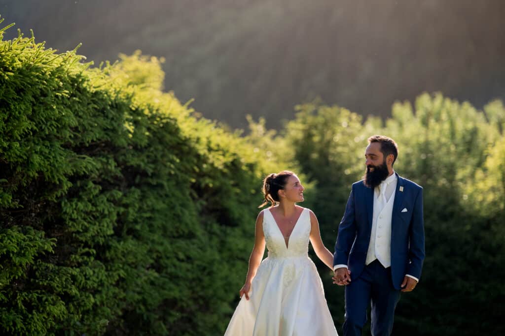 Couple de mariés à Chamonix – Lumière dorée en Haute-Savoie Couple de mariés marchant main dans la main lors d’un mariage à Chamonix en Haute-Savoie, photographié dans une lumière de fin de journée.